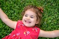 Happy Smiling Little Toddler Girl Laying On Grass In Park With Red Dress Royalty Free Stock Photo