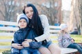 Happy smiling & looking at camera beautiful mother hugging or holding son young boy, sitting lonely one little girl