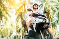 Tourist in safety helmet ride a motoroler under palm trees
