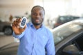 Happy smiling man holding car keys offering new car on background Royalty Free Stock Photo