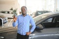 Happy smiling man holding car keys offering new car on background Royalty Free Stock Photo