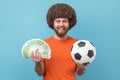 Happy smiling man holding soccer ball and fan of euro bills, sports betting, big win. Royalty Free Stock Photo