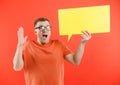 Happy smiling man holding yellow bubble speech, looking at camera over red background Royalty Free Stock Photo