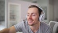 Happy smiling man listening to music in headphones at home