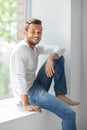 Happy smiling man relaxing on window sill Royalty Free Stock Photo