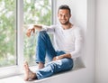 Happy smiling man relaxing on window sill Royalty Free Stock Photo