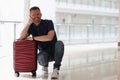 Happy smiling man is sitting suitcase in hotel