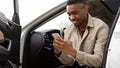 Happy smiling man typing a message on the phone while sitting in the car. Royalty Free Stock Photo