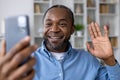 Happy smiling man using app on phone for video call, african american man smiling and looking at smartphone camera Royalty Free Stock Photo