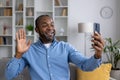 Happy smiling man using app on phone for video call, african american man smiling and looking at smartphone camera Royalty Free Stock Photo