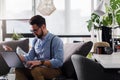 Happy smiling man using debit card working on laptop computer while sitting on sofa Royalty Free Stock Photo