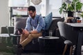 Happy smiling man using smart device and working on laptop computer while sitting on sofa Royalty Free Stock Photo