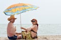 Happy smiling mature couple sitting at seashore on sandy beach outdoors Royalty Free Stock Photo