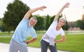 Happy smiling mature man and woman in sportswear stretching body while warming up together outdoors Royalty Free Stock Photo