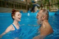 Happy smiling mature man and young woman swimming in pool Royalty Free Stock Photo