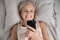 Happy smiling mature woman having fun with cellphone top view