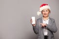 Happy smiling mature woman in red Santa hat holding smart phone with empty display Royalty Free Stock Photo