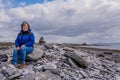 Happy and smiling Mexican woman sitting on the stones of the rocky beach of Inis Oirr Island