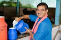 Happy smiling milk dairy farmer busy working while looking at camera - concept of milk production agri busines, rural