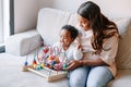 Happy smiling mixed race Indian mother and African black baby toddler playing developmental wooden bead maze toy game together at Royalty Free Stock Photo