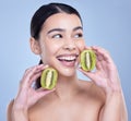 A happy smiling mixed race woman holding a kiwi fruit. Hispanic model promoting the skin benefits of a healthy diet