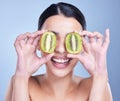 A happy smiling mixed race woman holding a kiwi fruit. Hispanic model promoting the skin benefits of a healthy diet