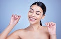 A happy smiling mixed race young woman with glowing skin posing against blue copyspace background while flossing her Royalty Free Stock Photo