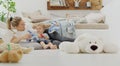 Happy and smiling mom with baby playing in living room at home with plush stuffed animals toys, sitting on the floor with pillows Royalty Free Stock Photo