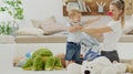 Happy and smiling mom with baby playing in living room at home with plush stuffed animals toys, sitting on the floor with pillows Royalty Free Stock Photo