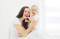 Happy smiling mother and baby at home in white room Royalty Free Stock Photo