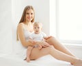 Happy smiling mother and baby home in white room near window Royalty Free Stock Photo