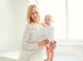 Happy smiling mother with baby home in white room Royalty Free Stock Photo