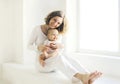 Happy smiling mother with baby home in white room near window Royalty Free Stock Photo