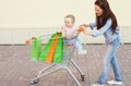 Happy smiling mother and child with trolley cart and shopping bags Royalty Free Stock Photo
