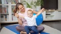 Happy smiling mother doing gymnastics and fitness exercises with her 1 year old baby boy on mat at home. Concept of healthcare, Royalty Free Stock Photo