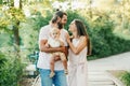 Happy smiling mother and father with baby boy in park outdoor. Family Caucasian mom and dad with son walking hugging in park on a Royalty Free Stock Photo