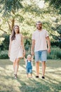 Happy smiling mother and father hold hands with baby boy in park outdoor. Family Caucasian mom and dad with son walking together. Royalty Free Stock Photo