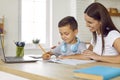 Happy, smiling mother helping her little son while he is doing his school homework Royalty Free Stock Photo