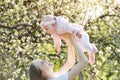 Happy smiling mother holding young daughter on flowering trees background. Child and parenthood concept Royalty Free Stock Photo