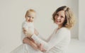 Happy smiling mother and little baby together in white room at home Royalty Free Stock Photo