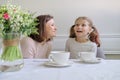 Happy smiling mother and little daughter drinking at table of cups Royalty Free Stock Photo