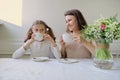 Happy smiling mother and little daughter drinking at table of cups Royalty Free Stock Photo