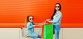 Happy smiling mother and little girl child with trolley cart and shopping bags in the city Royalty Free Stock Photo