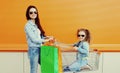 Happy smiling mother and little girl child with trolley cart and shopping bags in city Royalty Free Stock Photo