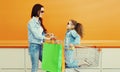 Happy smiling mother and little girl child with trolley cart and shopping bags in city Royalty Free Stock Photo