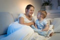 Happy smiling young mother looking at her baby boy lying in bed at night Royalty Free Stock Photo