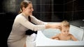 Happy smiling mother looking at her baby son relaxing and washing in bath at home. Concept of parenting, happiness and child Royalty Free Stock Photo