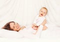 Happy smiling mother playing with baby lying on bed home Royalty Free Stock Photo