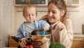 Happy smiling mother playing with ladle and her baby son while cooking on kitchen. Concept of little chef, children cooking food, Royalty Free Stock Photo