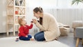 Happy smiling mother sitting on floor and playing with her little baby son. Baby development, family playing games, having fun Royalty Free Stock Photo